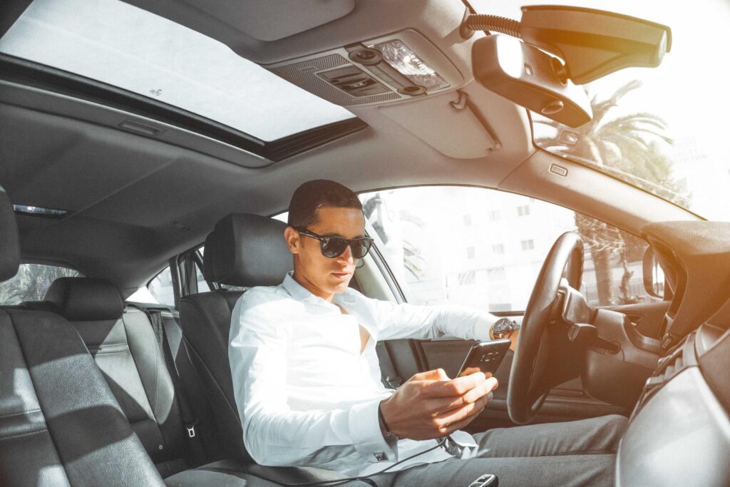 A man texting in sunglasses texting while driving