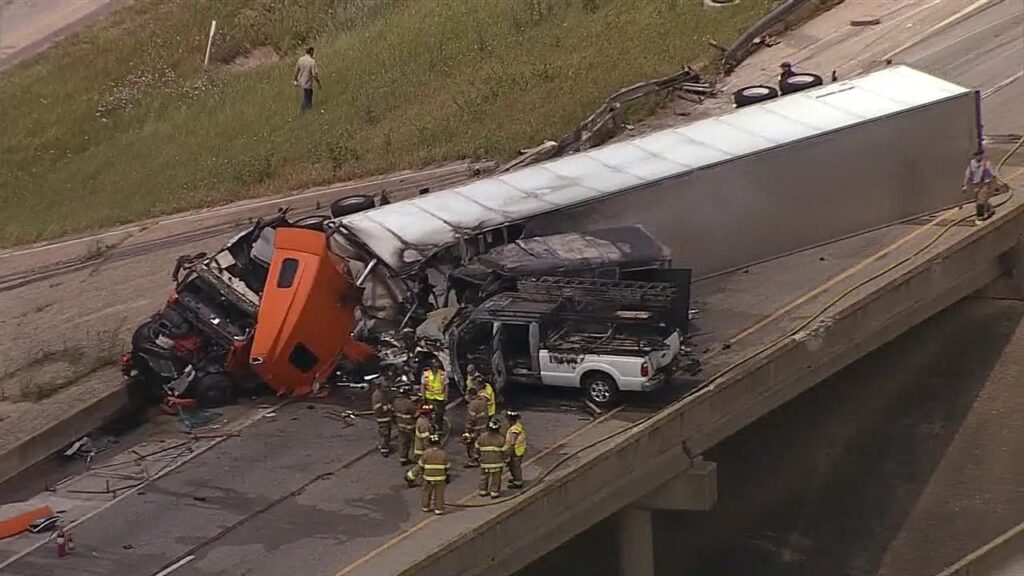 A semi truck flipped over on the highway with emergency crew nearby.